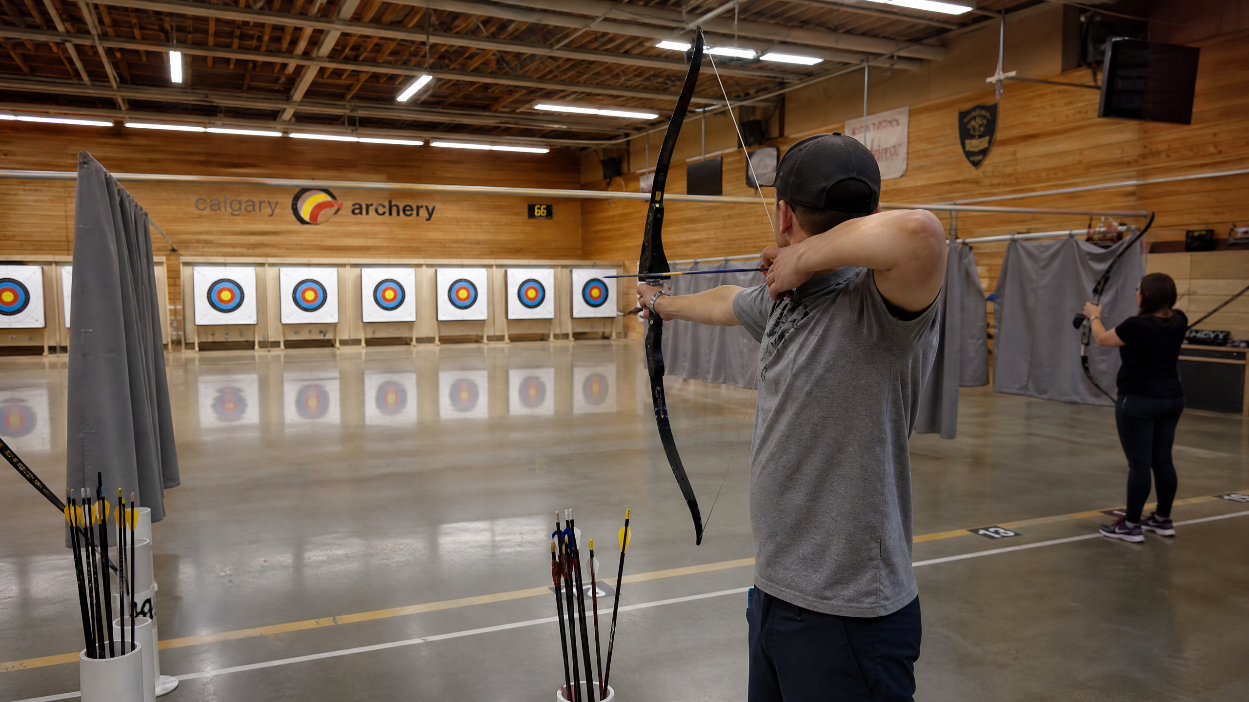 Indoor archery range with a warm wood interior and a recurve bow on the line