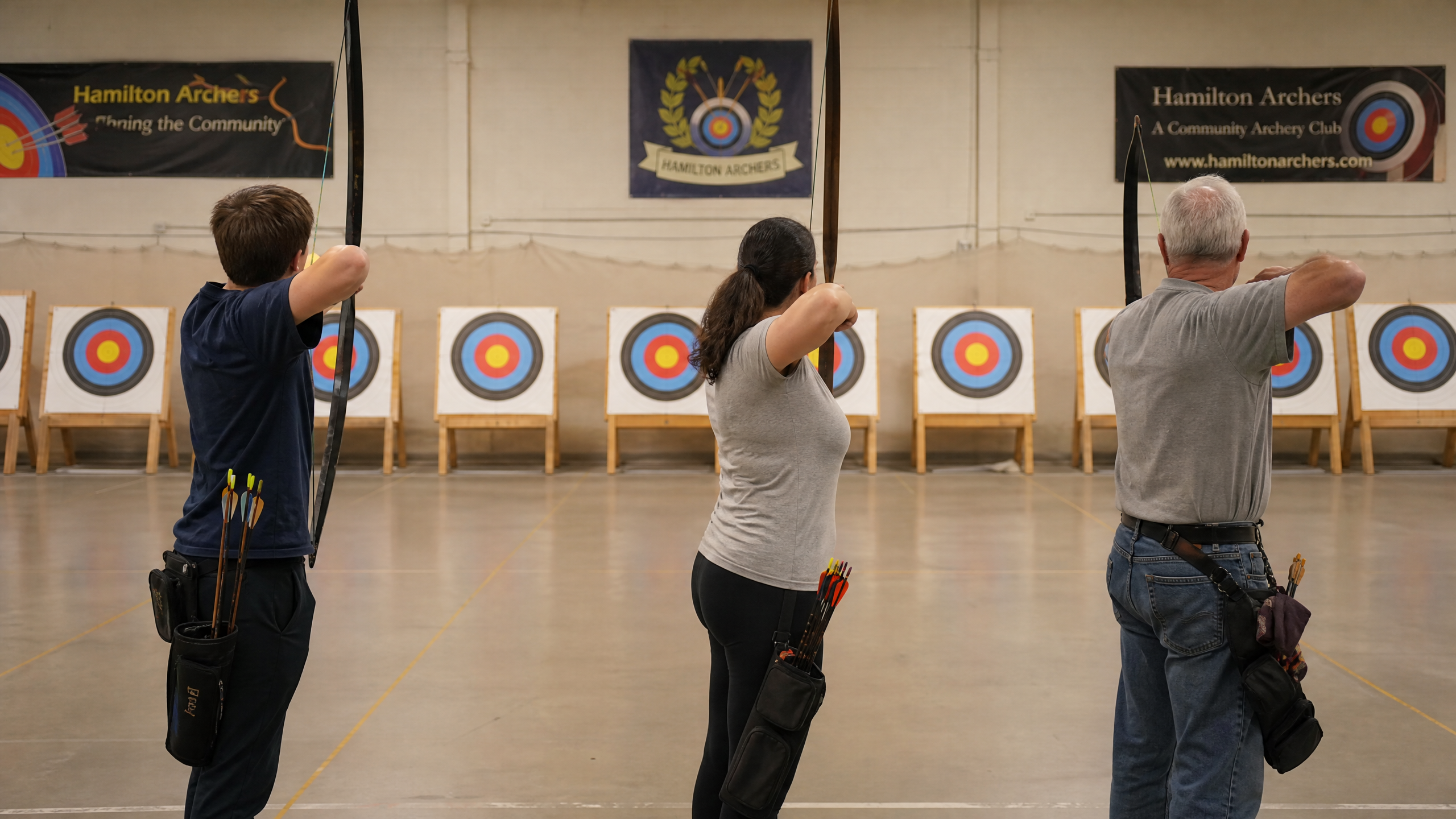 Community archery club with mixed-age archers on an indoor range